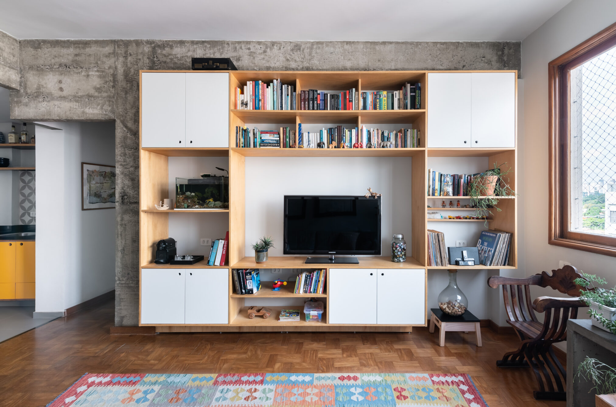Living compacto com estante e tapete em projeto da Labra