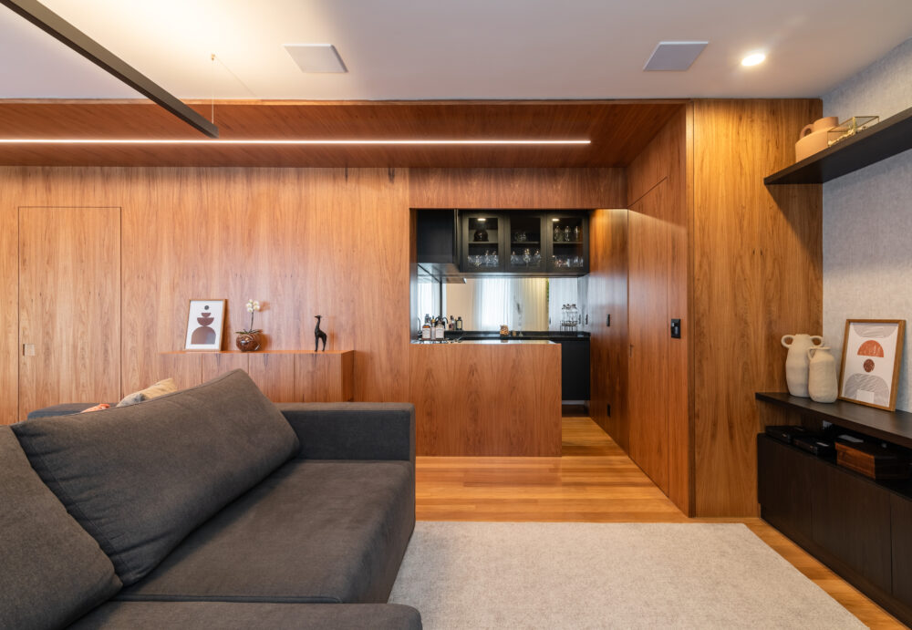 Sala de estar com painéis de madeira e iluminação indireta em projeto da Labra