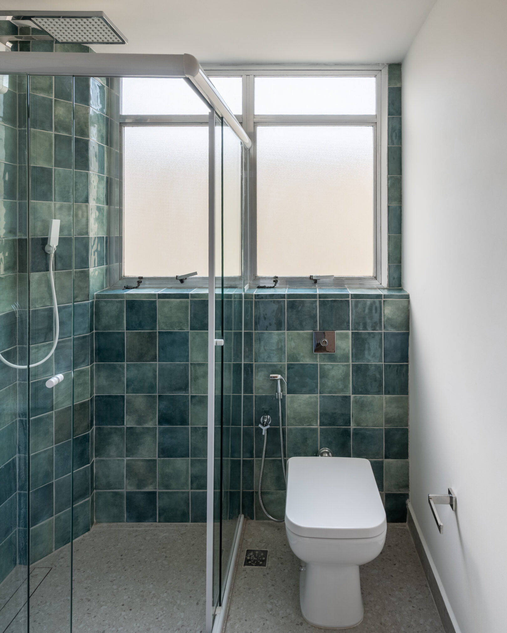 Banheiro com revestimento verde e espelho em projeto residencial da Labra