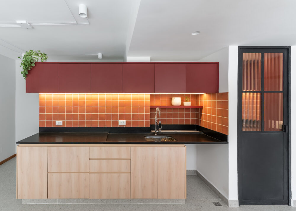 Cozinha com revestimento terracota e iluminação quente em projeto da Labra